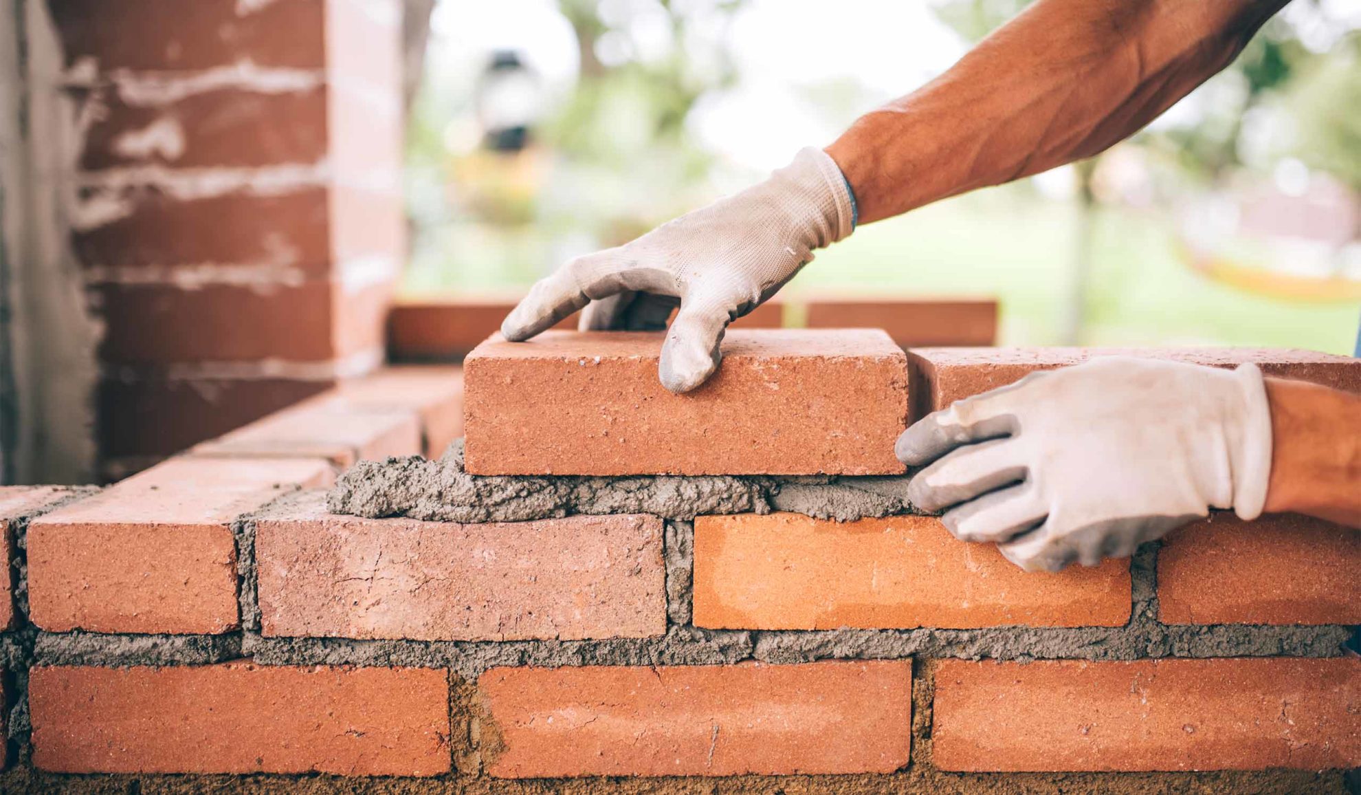 contractor hand close up with construction glove building a masonry brick wall at property blue ridge mo